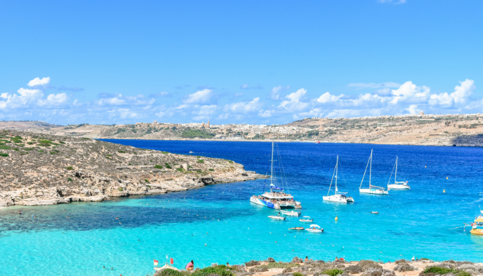 Türkisblaue Bucht in Malta mit ankernden Segelbooten und Katamaranen